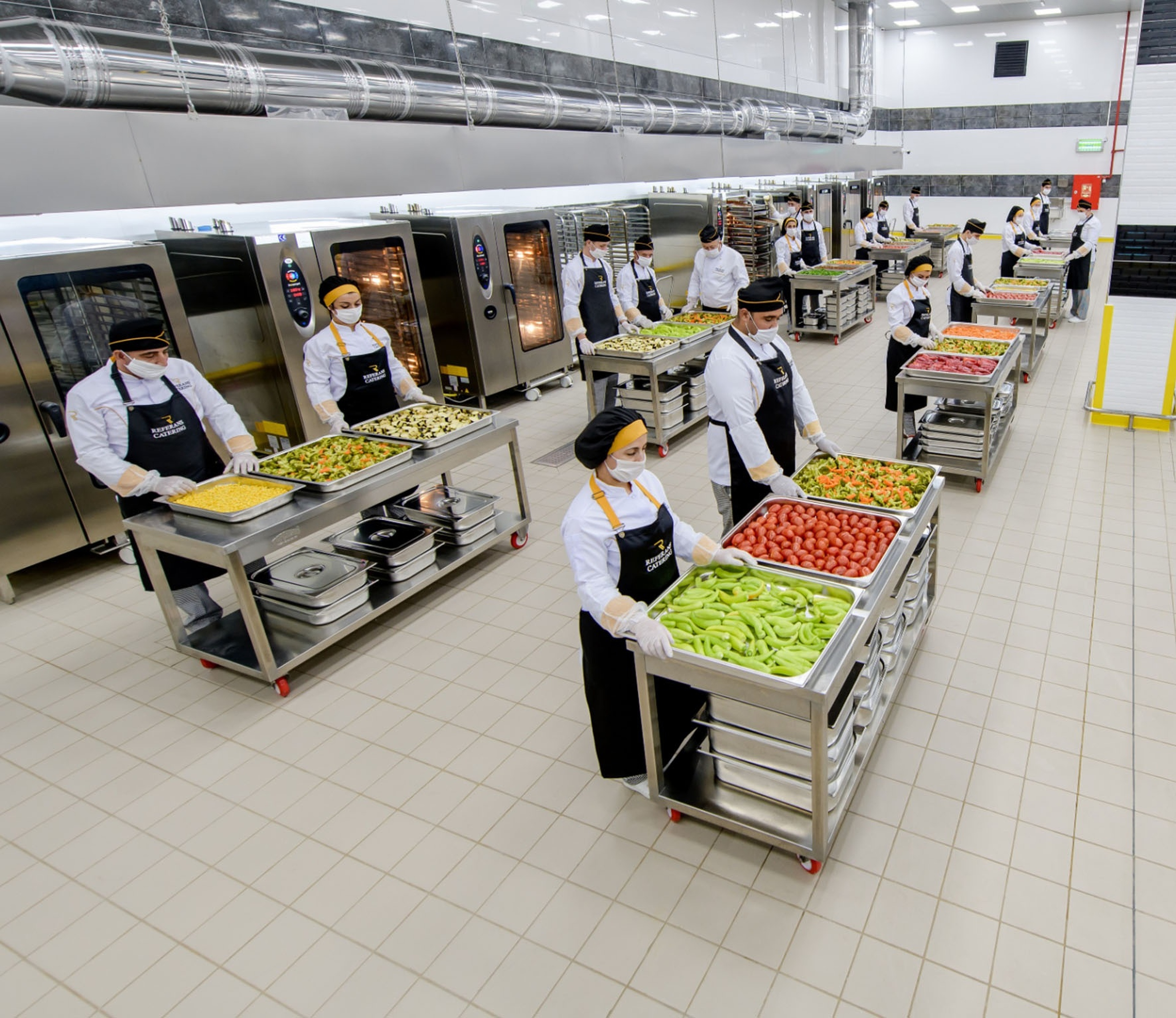 Large-scale central food production team working across stainless-steel stations